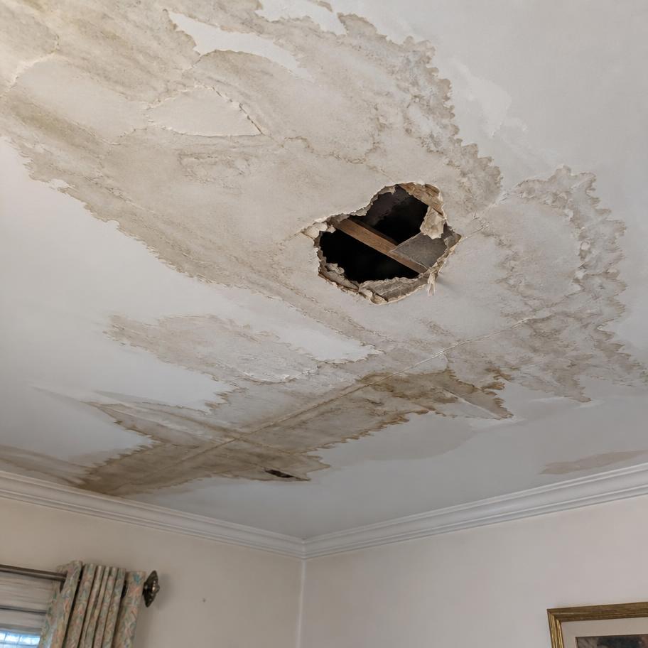 Cielo interior de vivienda con manchas de humedad y perforación por ingreso reciente de agua lluvia